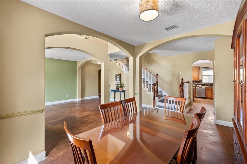 1305 Liverpool Lane Mansfield, TX 76063 - Photo 7 of 40 The property features a spacious interior with arched doorways, a visible staircase, and a kitchen with wooden cabinetry and stainless steel appliances