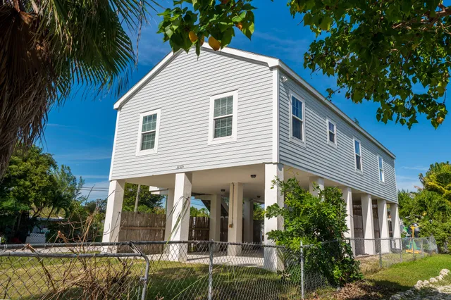 a view of a white house with a large windows and flower plants