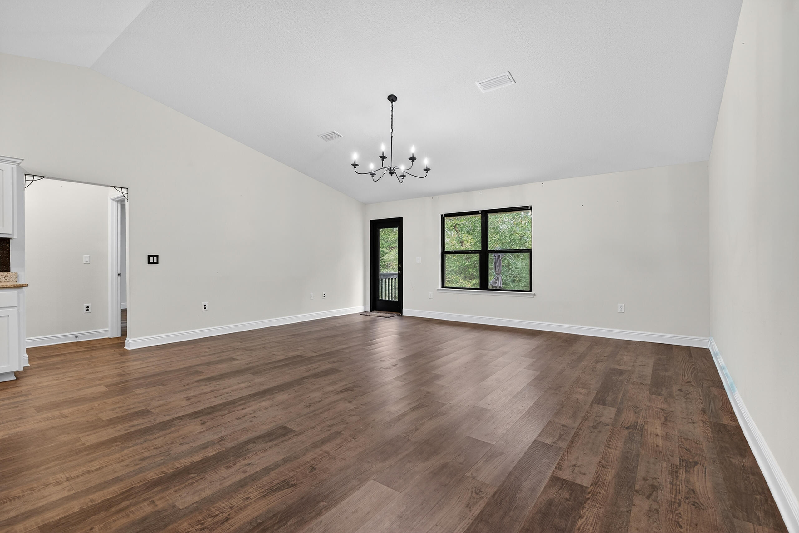 5733 Marigold Loop Crestview, FL 32539 - Photo 14 of 45 an empty room with wooden floor chandelier and windows
