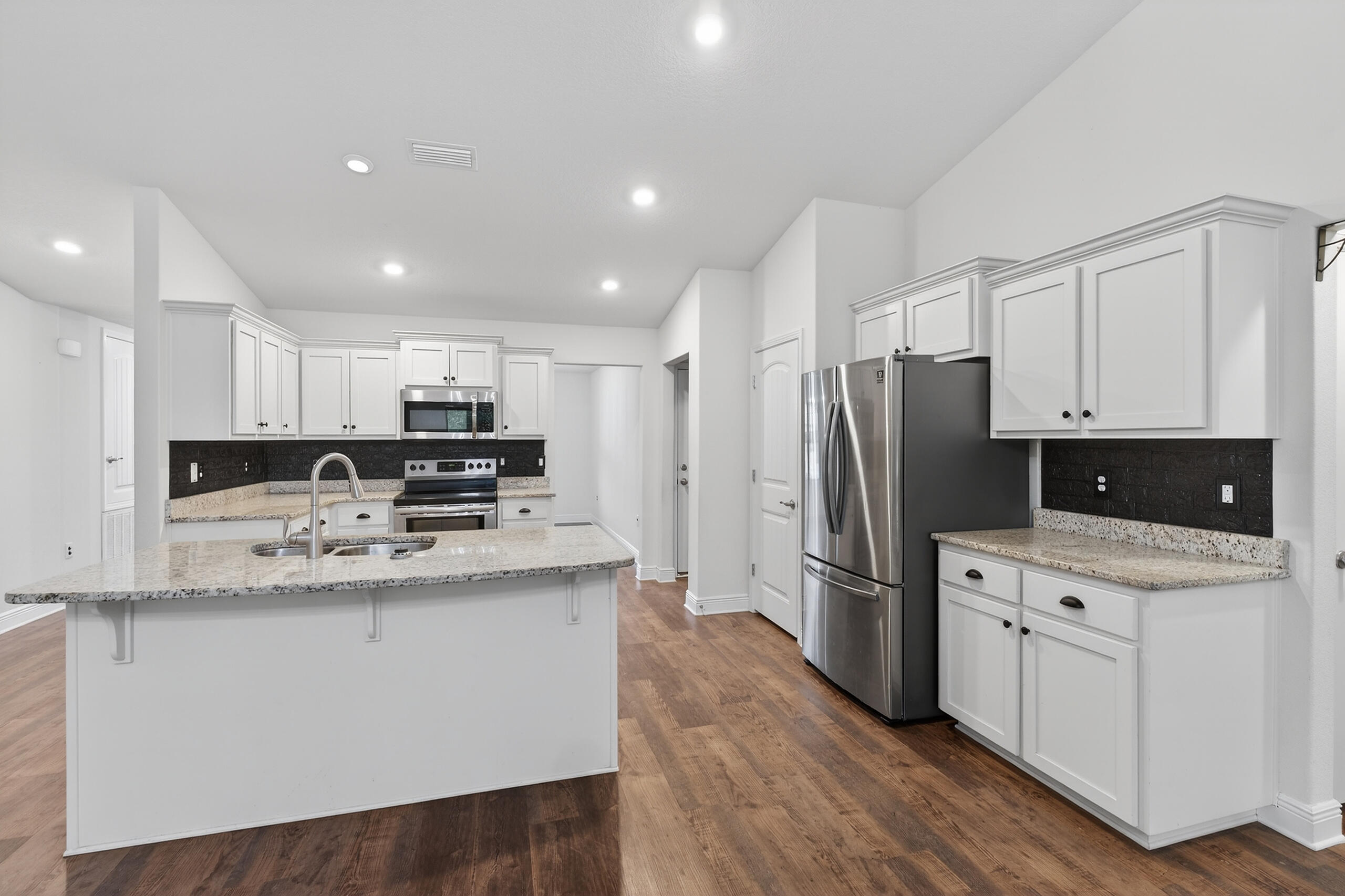 5733 Marigold Loop Crestview, FL 32539 - Photo 18 of 45 a kitchen with stainless steel appliances granite countertop a refrigerator a stove a sink and white cabinets with wooden floors