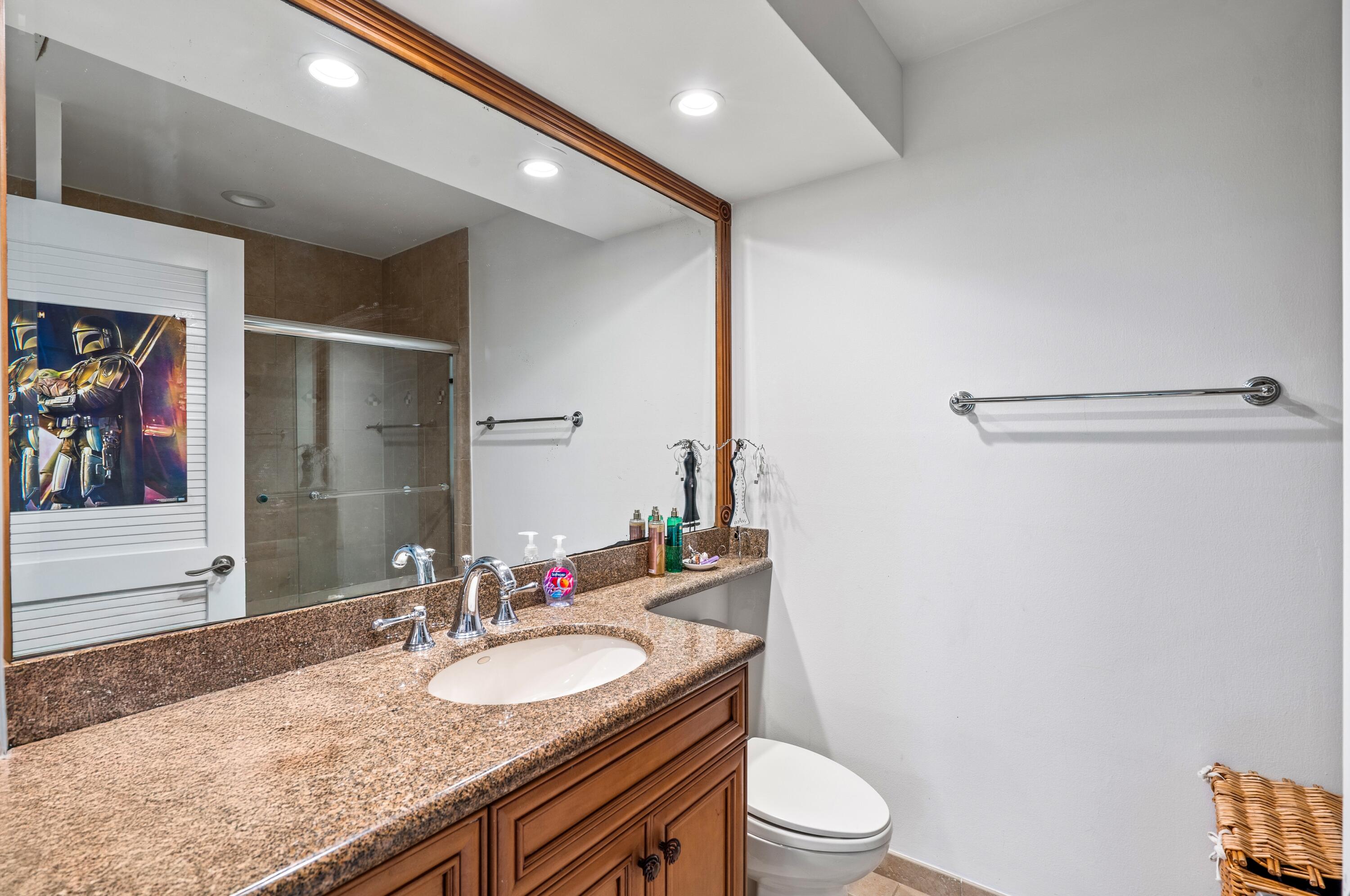3098 Northwest 60th Street Boca Raton, FL 33496 - Photo 24 of 30 a bathroom with a granite countertop sink a toilet a mirror and shower