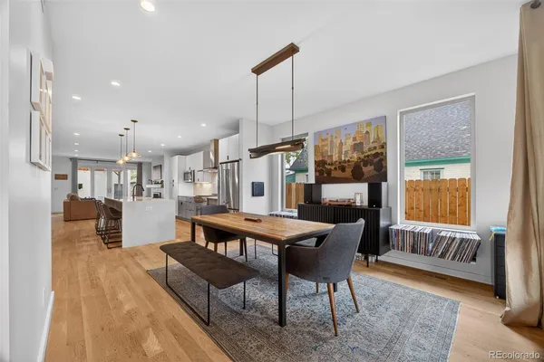 a kitchen with stainless steel appliances granite countertop a stove a sink a refrigerator and white cabinets with wooden floor