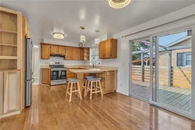 a kitchen with stainless steel appliances a dining table chairs and wooden floor