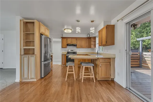 a kitchen with granite countertop a stove a sink dishwasher a refrigerator cabinets and wooden floor