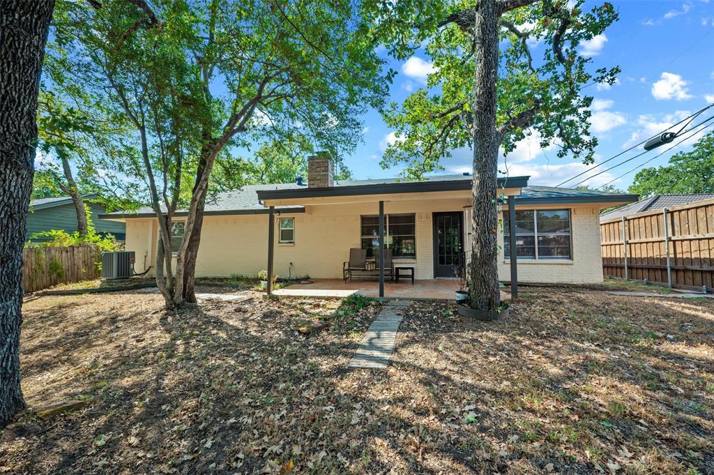 608 Ridgewood Circle Hurst, TX 76054 - Photo 33 of 38 Exterior featuring a covered patio, brick chimney, privacy fencing, and mature trees