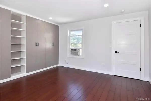 a view of an empty room with a window and wooden floor