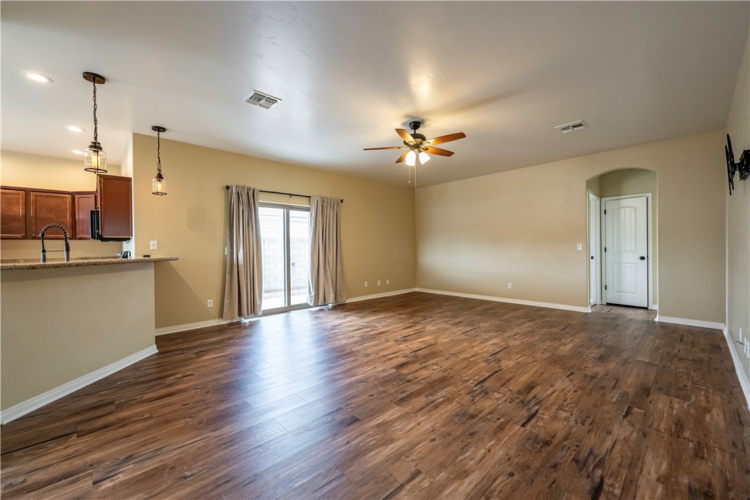 3546 North Kenneth Road Kingman, AZ 86409 - Photo 9 of 35 The living area features wood-style flooring, a ceiling fan, and sliding glass doors with curtains providing access to the outdoors