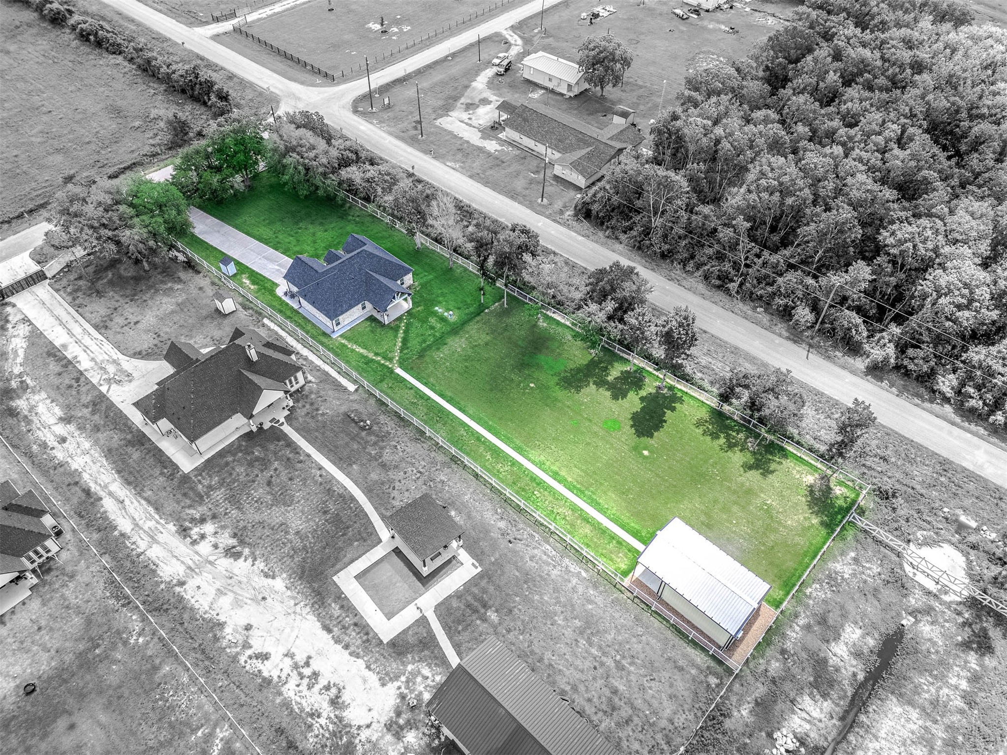 8032 Short Road Needville, TX 77461 - Photo 42 of 50 This aerial perspective showcases the full layout of the property, including the main residence, expansive lawn, fenced areas, and additional outbuilding. The setting offers a great combination of privacy, usable outdoor space, and convenient access along a quiet roadway.