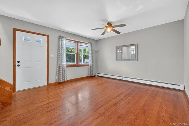 a view of an empty room with a window and wooden floor