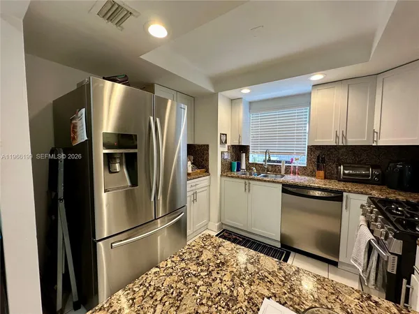 a kitchen with stainless steel appliances granite countertop a refrigerator sink and stove