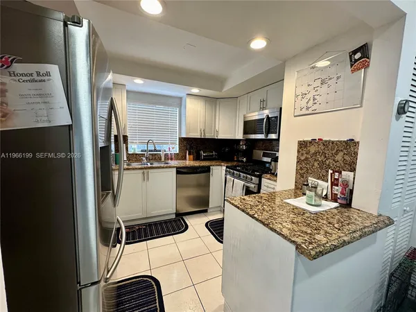 a kitchen with kitchen island granite countertop a stove top oven a sink a counter top space and cabinets