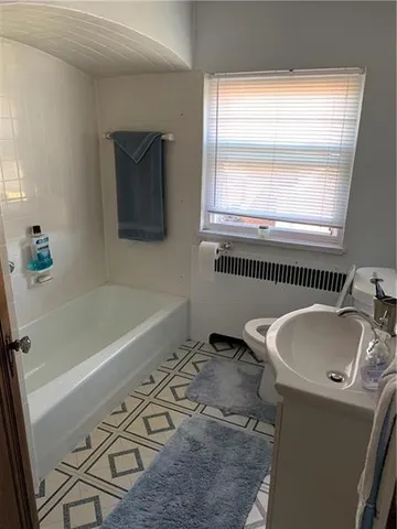 a bathroom with a sink a bathtub and next to a window