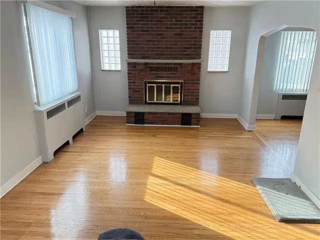 a view of empty room with wooden floor and fireplace