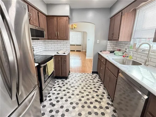 a kitchen with granite countertop a sink a stove a refrigerator and cabinets