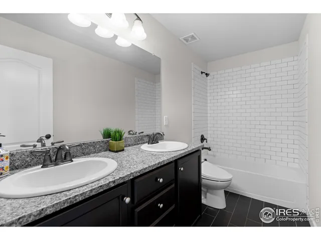 a bathroom with a granite countertop sink a toilet and a mirror