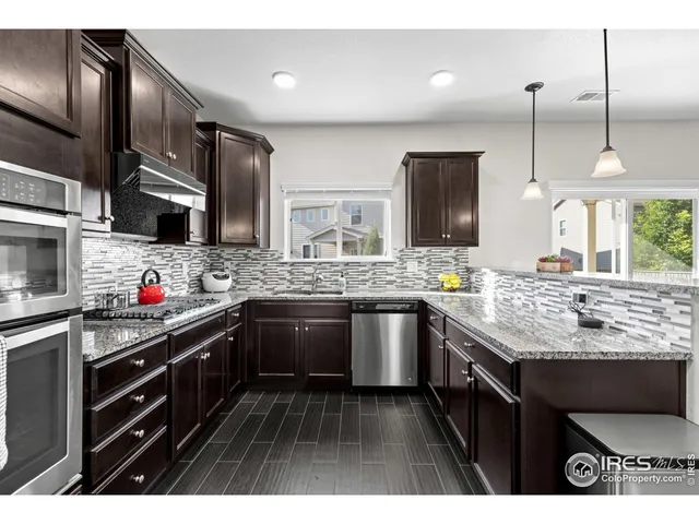 a kitchen with stainless steel appliances granite countertop a sink a stove and a wooden floors
