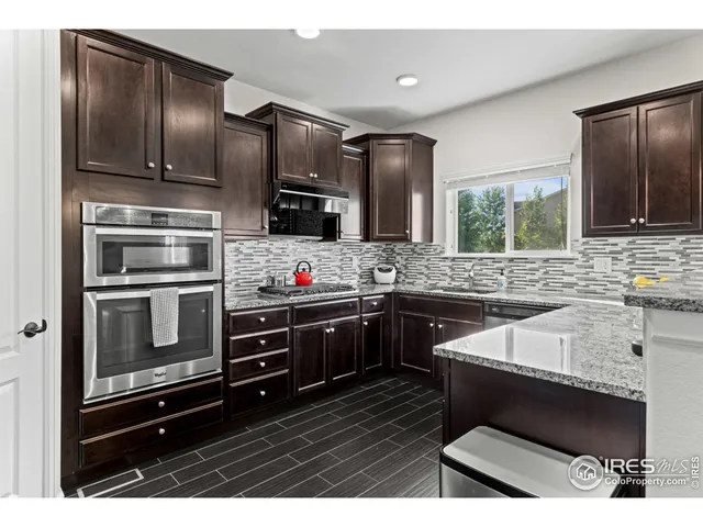 a kitchen with stainless steel appliances kitchen island granite countertop a refrigerator stove and sink