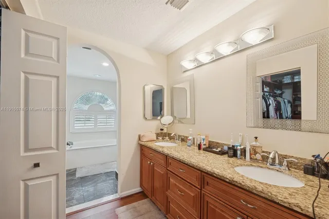 a bathroom with a granite countertop double vanity sink and mirror