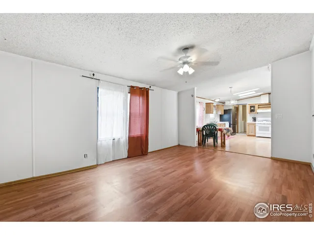 a view of an empty room with window a ceiling fan and wooden floor