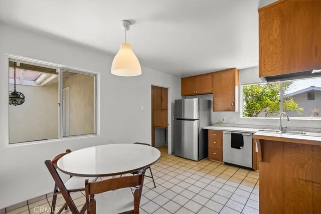 a kitchen with stainless steel appliances granite countertop a sink dishwasher a refrigerator a stove a kitchen island with a dining table and chair