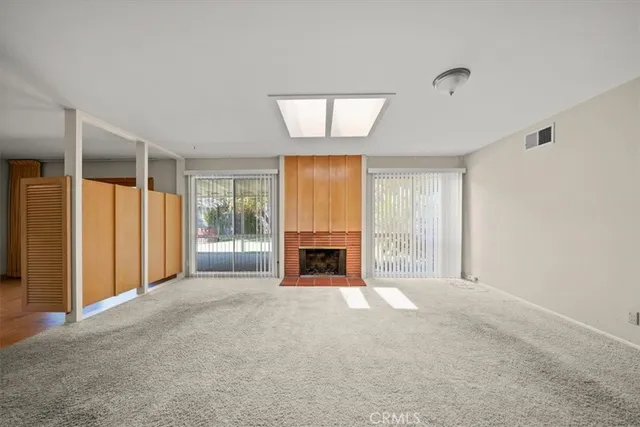 a view of a livingroom with a fireplace a ceiling fan and windows