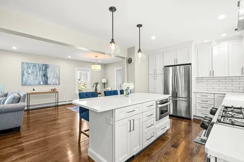 a large white kitchen with a refrigerator a sink dishwasher a dining table and chairs