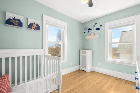 a view of an empty room with a window and wooden floor