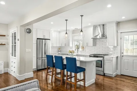 a kitchen with stainless steel appliances granite countertop a table chairs stove a refrigerator and cabinets