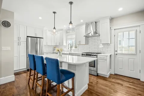 a kitchen with stainless steel appliances granite countertop a dining table chairs stove refrigerator and cabinets