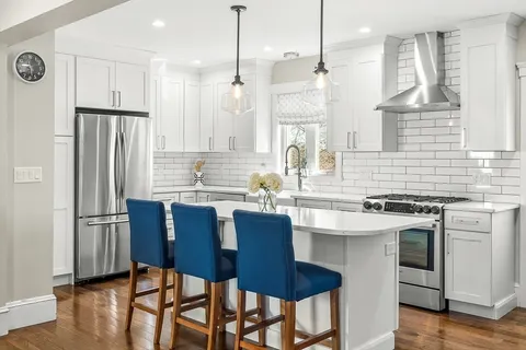a kitchen with stainless steel appliances granite countertop a stove a refrigerator a oven a sink with a dining table and chairs