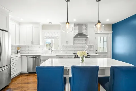 a kitchen with stainless steel appliances a dining table chairs sink and cabinets