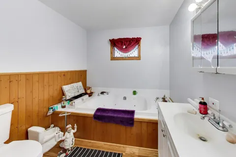 a bedroom with a bed and a dresser with wooden floor