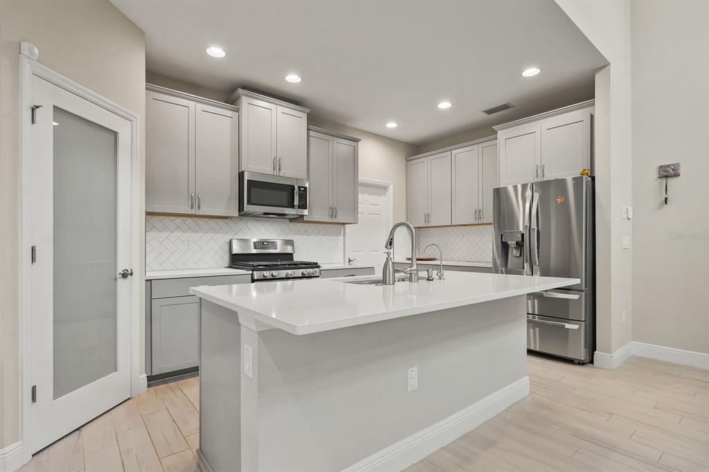 17880 Moon Rise Pass Land O Lakes, FL 34638 - Photo 8 of 43 a kitchen with kitchen island a sink stainless steel appliances and cabinets