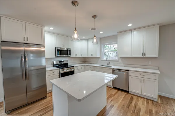 a kitchen with a center island white cabinets and stainless steel appliances