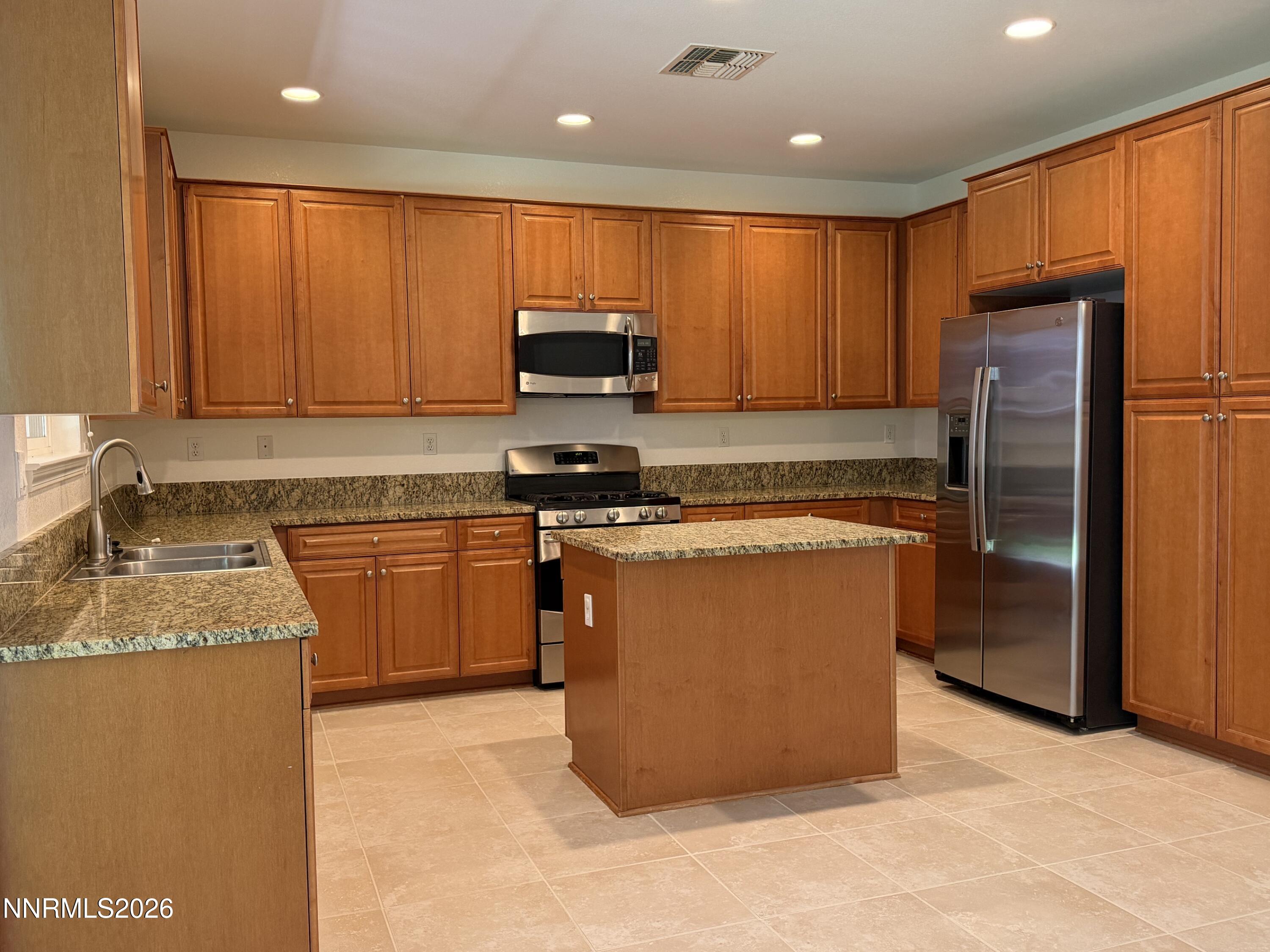 10890 Oakhaven Drive Reno, NV 89521 - Photo 6 of 28 a kitchen with stainless steel appliances granite countertop refrigerator a stove a sink and a microwave