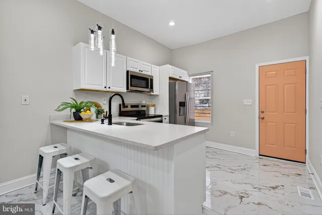 a kitchen with stainless steel appliances a sink a stove a refrigerator cabinets and a dining table