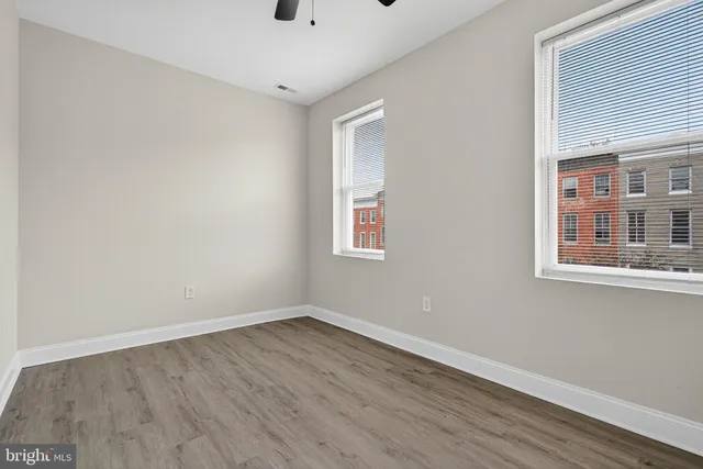 a view of empty room with wooden floor and fan