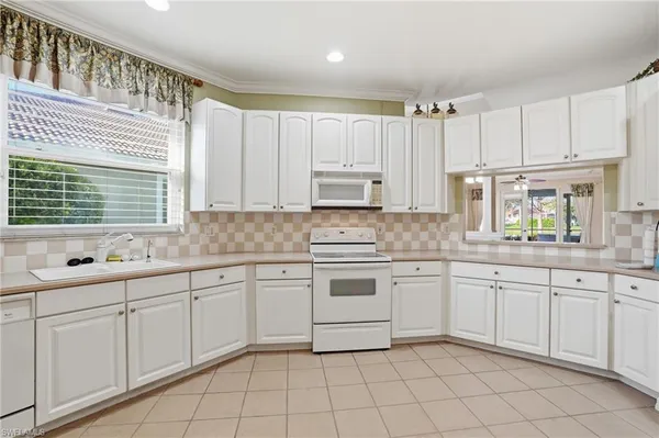 a kitchen with kitchen island granite countertop white cabinets white appliances with a sink and dishwasher