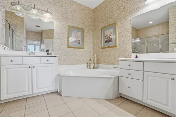 a spacious bathroom with a double vanity sink mirror and bathtub