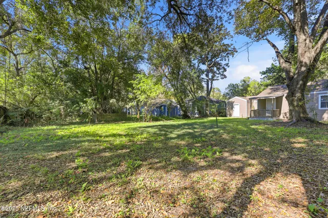 a view of a house with a small yard and a large tree