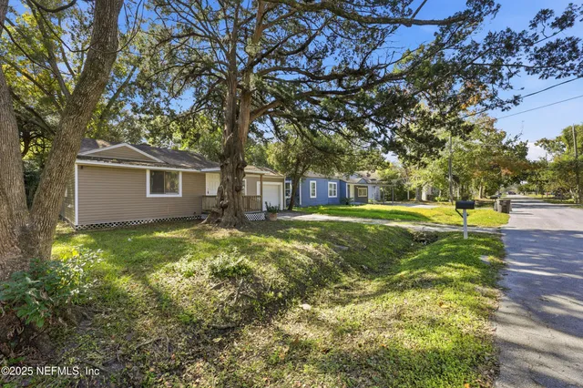 a view of a yard with a house and a large tree
