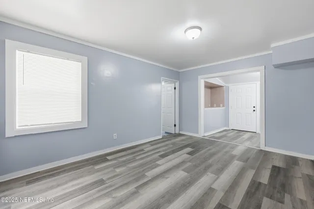 a view of an empty room with wooden floor and a window