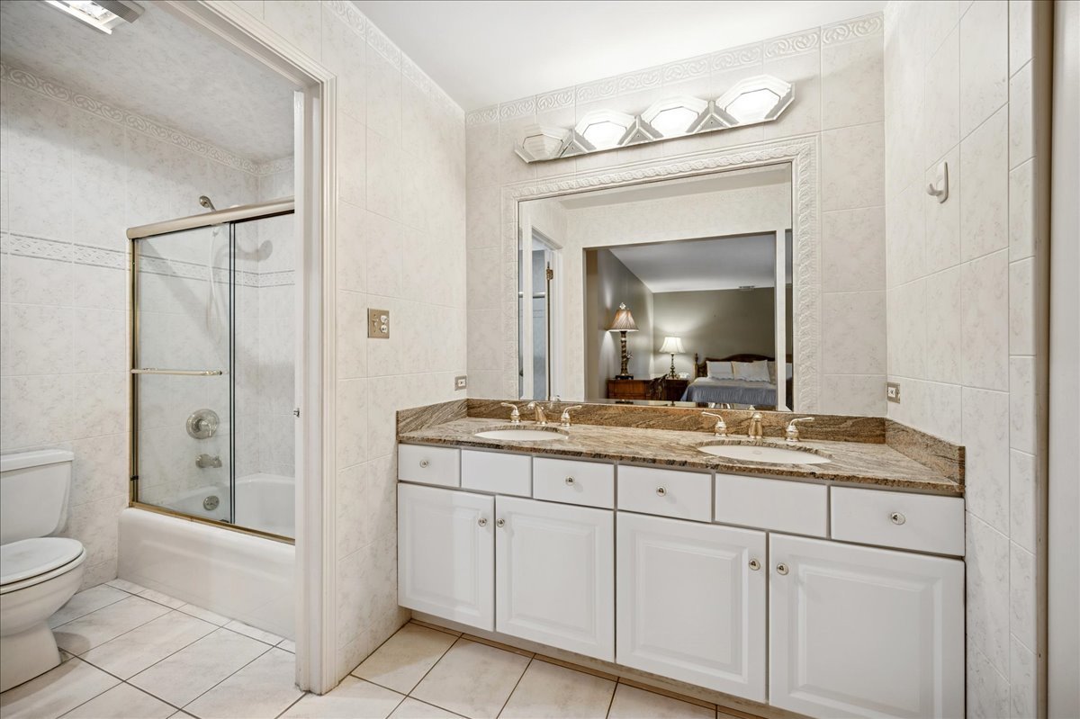 175 Lake Boulevard, Unit 301 Buffalo Grove, IL 60089 - Photo 10 of 15 a bathroom with a granite countertop sink a toilet and a mirror