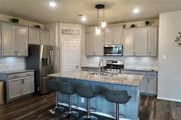 a kitchen with stainless steel appliances granite countertop a stove a sink a refrigerator and a microwave