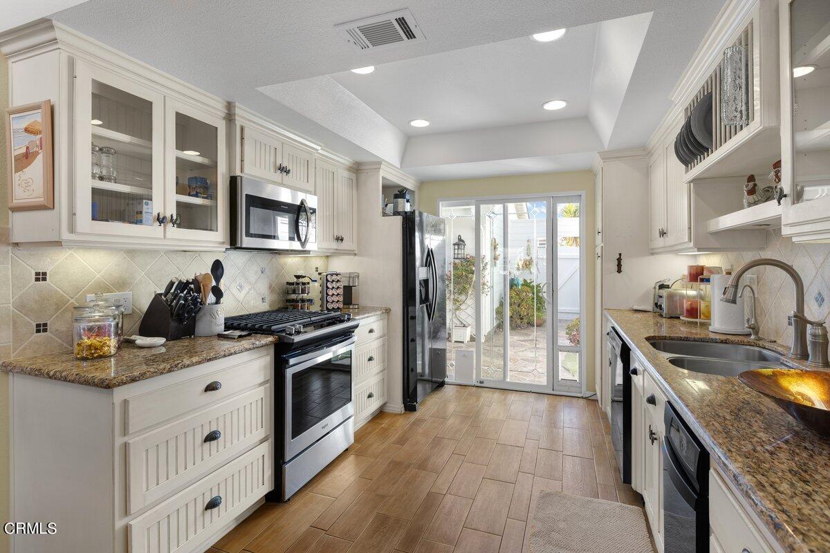 4620 Falkirk Bay Oxnard, CA 93035 - Photo 7 of 24 a kitchen with stainless steel appliances granite countertop a stove a sink dishwasher a refrigerator and a oven with wooden floor