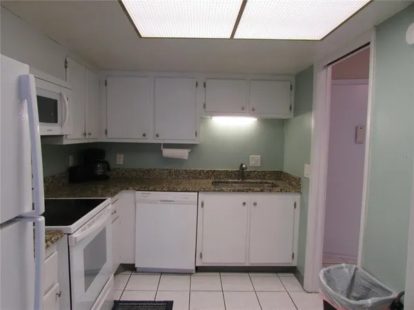 a kitchen with granite countertop white cabinets and white appliances