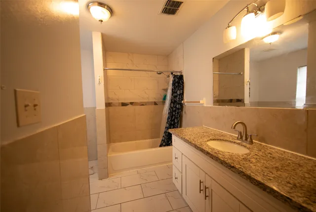 a bathroom with a granite countertop sink a mirror and a bathtub