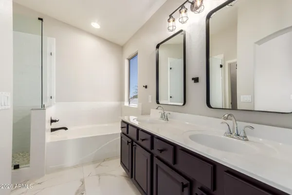 a bathroom with a sink double vanity granite tub shower and a mirror