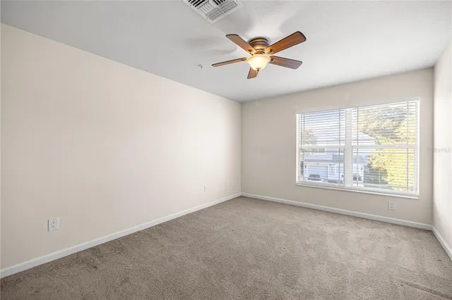 an empty room with windows and fan