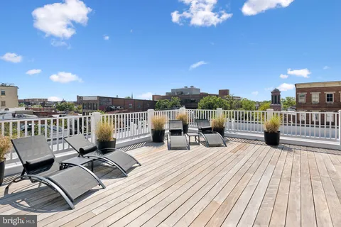 a view of a roof deck with table and chairs with wooden floor and fence